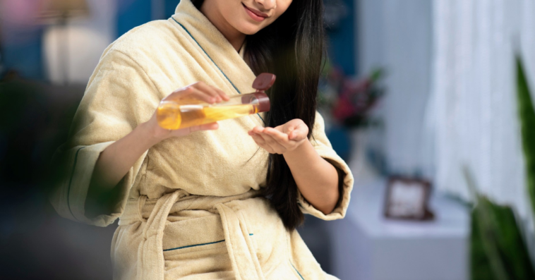 young woman pouring hair oil in her hand