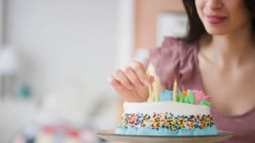 woman adds candles to a small birthday cake
