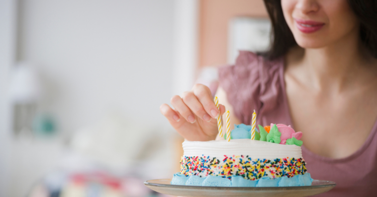 woman adds candles to a small birthday cake