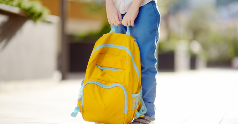 Child holding a backpack.