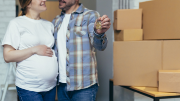 Pregnant woman and partner with moving boxes