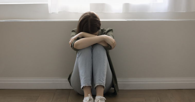 Teenage girl crying in a hallway.