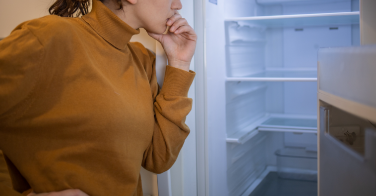 Woman looking into empty fridge.