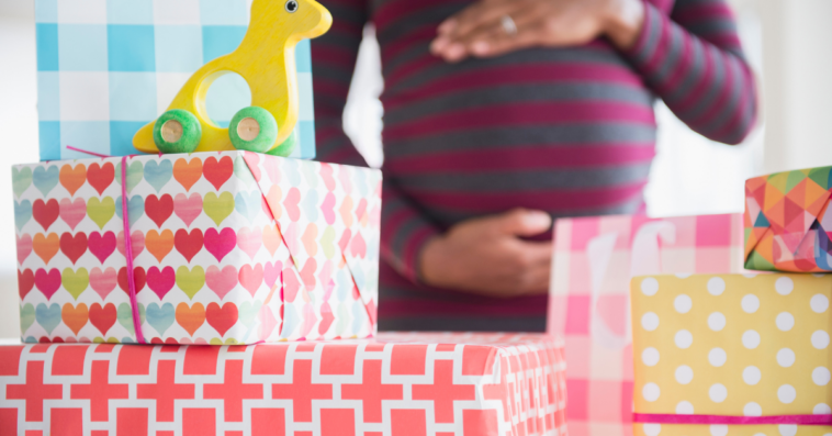 A pregnant woman holding her belly surrounded by gifts.