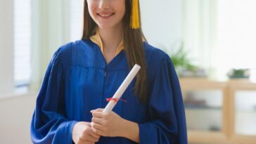 Teenage girl in graduation cap and gown, holding a diploma