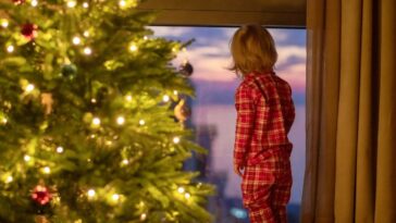 Child waiting for Santa Clause near a window in Christmas Eve