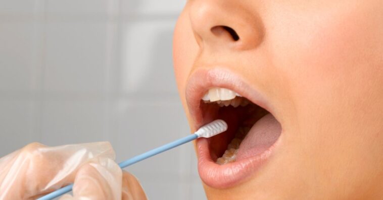 Person holding DNA swab in young woman's mouth