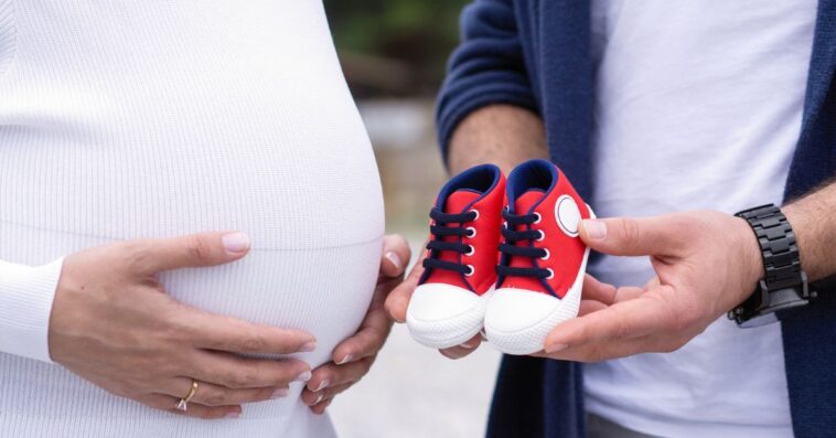 Couple holding baby boy shoes