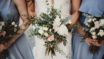 focus on bouquets of bride flanked by bridesmaids