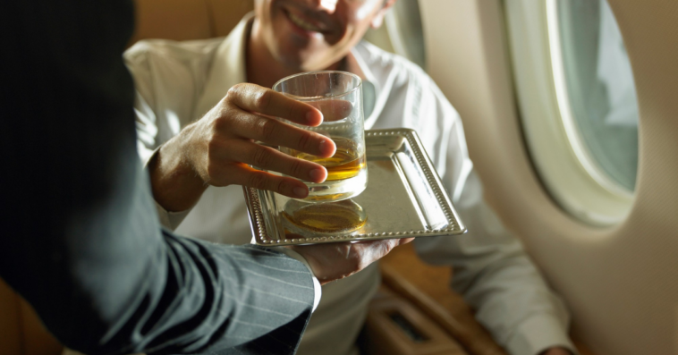 flight attendant serving male passenger a drink