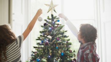 Children decorating a Christmas tree.