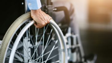Man holding onto the wheels of a wheelchair.