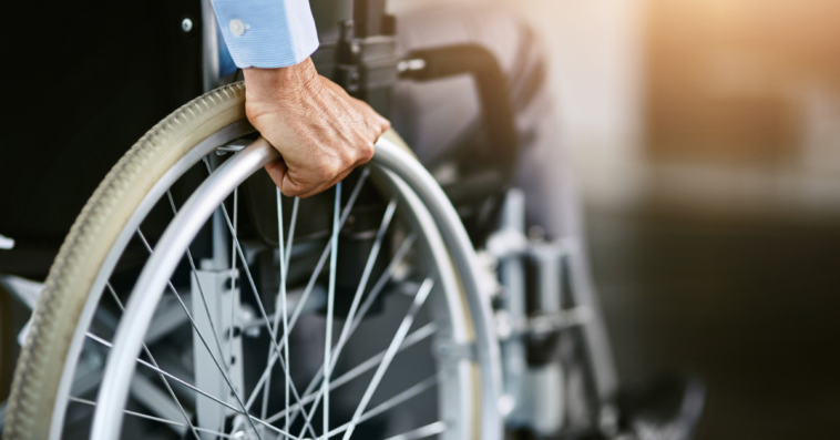 Man holding onto the wheels of a wheelchair.