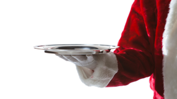Person in santa outfit holding a serving tray.