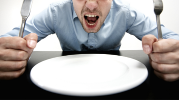 Angry and hungry man with empty plate