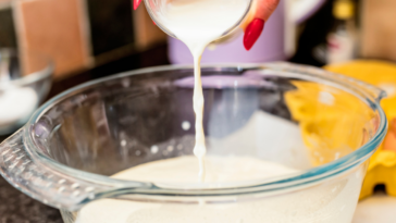 Woman pouring milk into a mixing bowl.