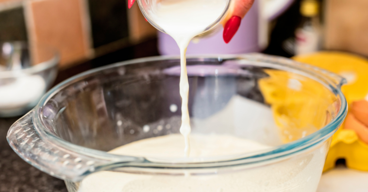 Woman pouring milk into a mixing bowl.
