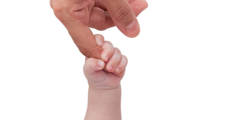 A child's hand holding an adult's index finger