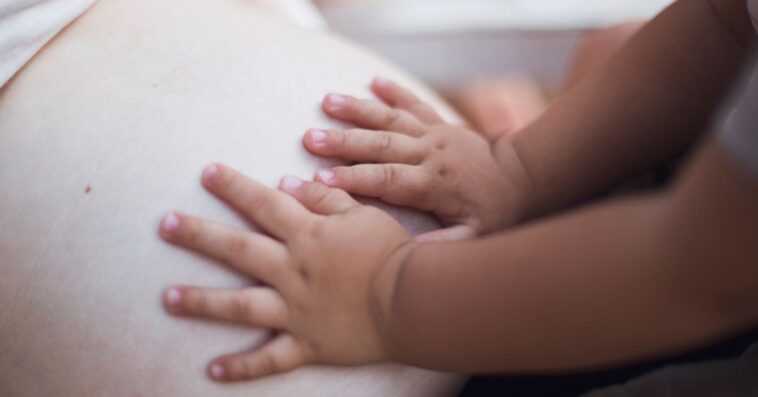 Baby hands on pregnant belly