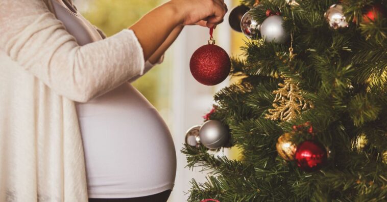Pregnant woman decorating Christmas tree