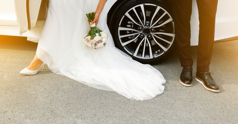 Bride and groom standing near car
