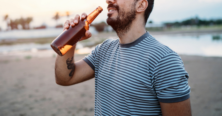 man drinking on the beach