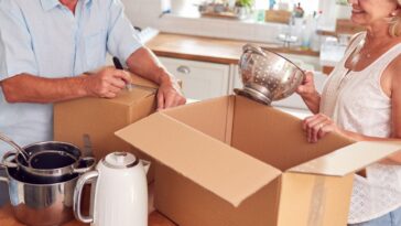 A Senior Couple is Downsizing for Retirement, Packing And Labelling Boxes Ready For Move Into New Home.