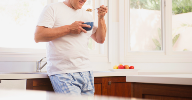A man wearing pajamas eating cereal.