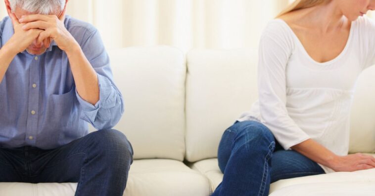 Upset married couple sitting on the sofa after a disagreement.