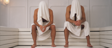 two men seated in a sauna