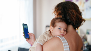 woman texting while holding baby