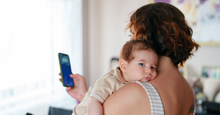 woman texting while holding baby