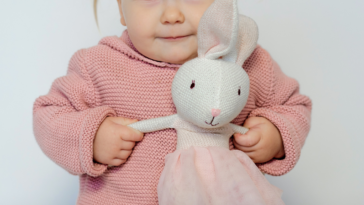 toddler playing with stuffed rabbit toy