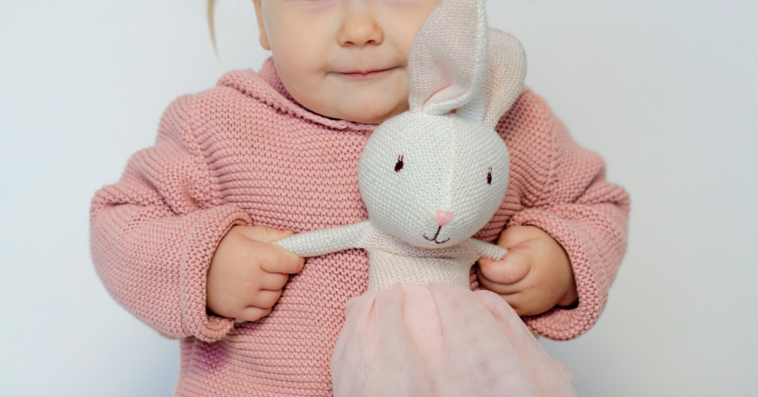 toddler playing with stuffed rabbit toy