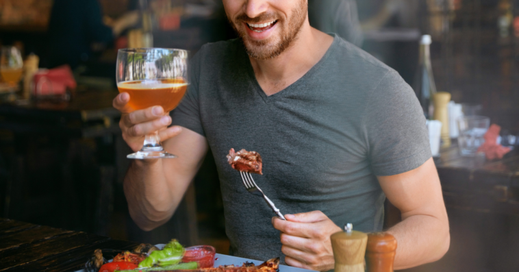 man drinking beer and eating steak