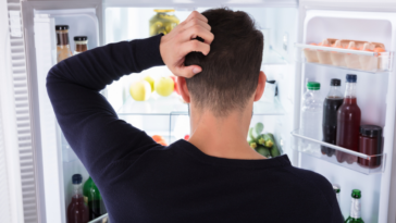 man looking at food in the fridge
