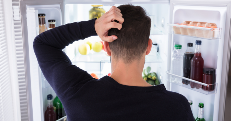 man looking at food in the fridge