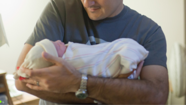 man holding infant in hospital