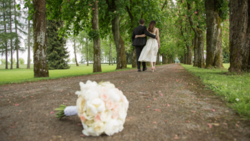 Bride and groom walking away with the bouquet fallen on the ground.