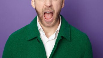 Head shot of an man shouting to camera against purple background