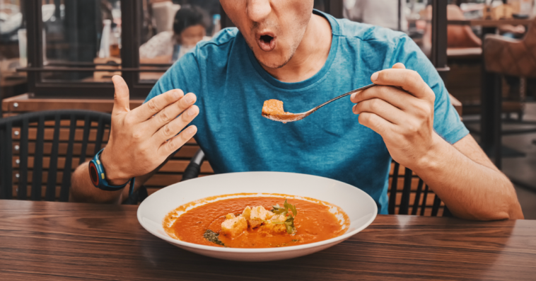 A man eating a spicy bowl of soup.