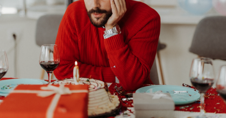 A man staring at his birthday cake.