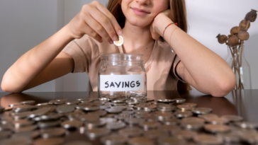 Teenage girl adding money to her college fund jar