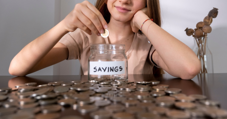 Teenage girl adding money to her college fund jar