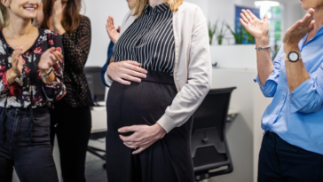 pregnant woman being applauded by coworkers