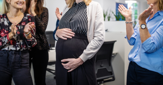 pregnant woman being applauded by coworkers