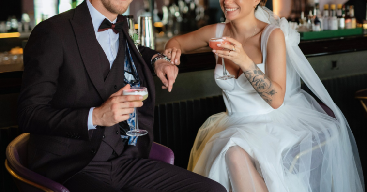 groom and bride sitting at a bar with cocktails