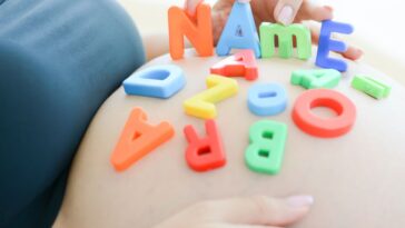 Expectant mother spelling name on her pregnant belly.