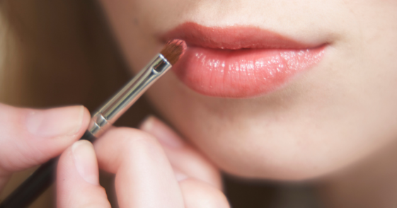 Teen girl applying lipstick