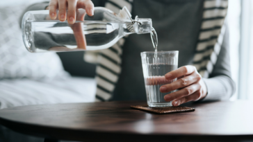 A woman pouring water into a glass.